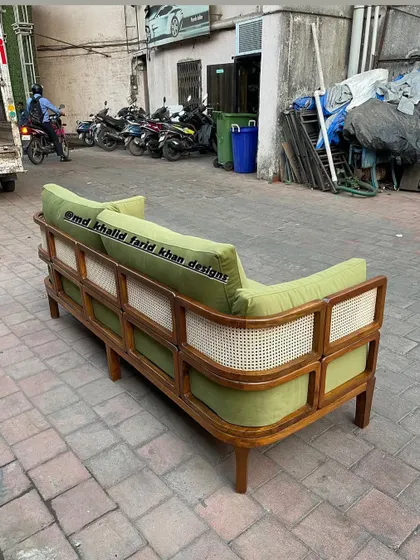 The back of the green sofa, showcasing the extensive cane work that wraps around the frame.