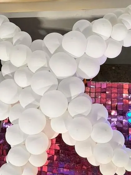A close up detail from a mermaid party, showing a starfish made of white balloons and a neon mermaid sign against a shimmer wall.