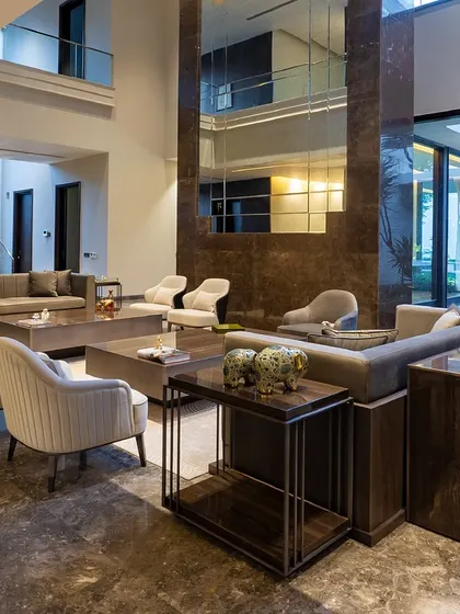 The main living area of a New Delhi farmhouse, where our custom furniture complements the grand scale of the space. Neutral tones and natural light create a seamless blend with the surrounding greenery.