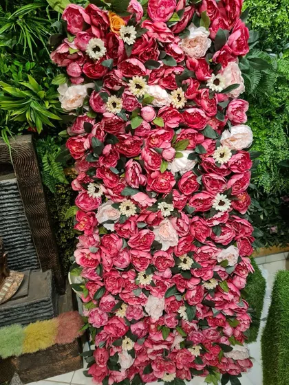 I can create unique decorative pieces like this wall panel made entirely of artificial pink and white flowers. It serves as a beautiful photo backdrop or accent wall for events and businesses.