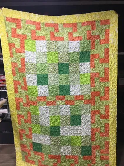 A bright and cheerful quilt in greens, oranges, and yellows.
