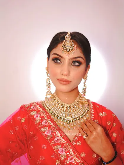 A close-up portrait in the red and pink lehenga, showing the beautiful bridal jewelry it pairs with.