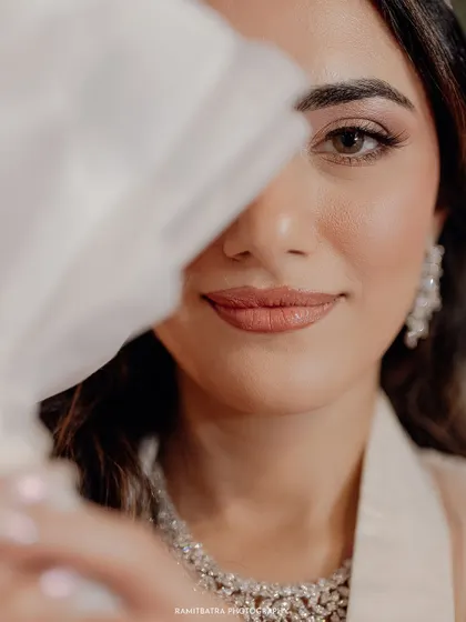 A captivating close-up of a bride in Bangladesh, her face partially hidden by her white veil, drawing focus to her expressive eyes.