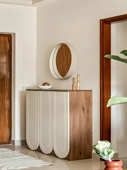 A chic and minimalist console table for a modern entryway. The design features unique rounded, fluted doors and a combination of white and wood finishes for a soft and contemporary look.
