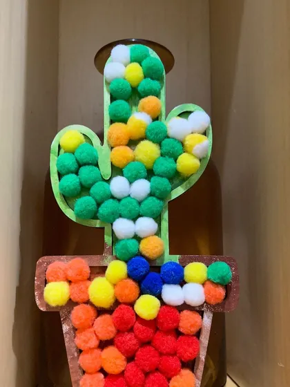 A finished pom-pom cactus, full of vibrant colors. This is a great example of the fun and creative pieces kids can make.