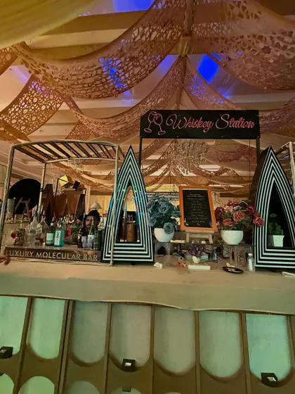 A full view of our Art Deco 'Whiskey Station', featuring a striped counter, unique decor pieces, and a clear menu for guests.