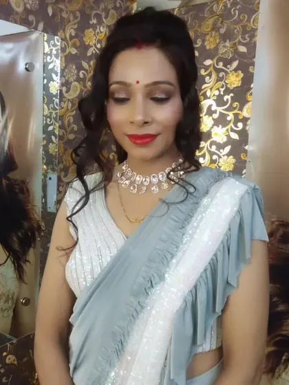 A classic party makeup look. This features a simple yet elegant hairstyle, defined eyes, and a bold red lip that stands out beautifully against the grey saree.