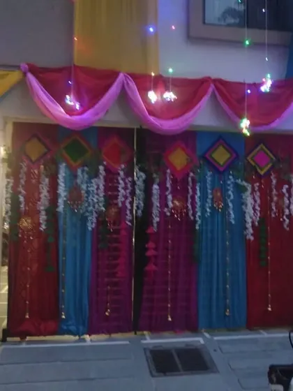 The decorated house gate at night, with lights adding a festive sparkle to the colorful fabric drapes.