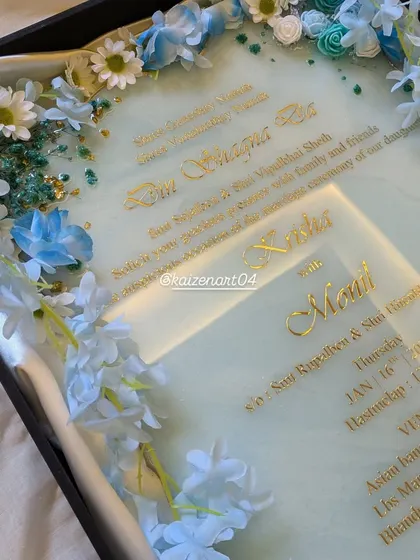 A closer look at the details on the blue wedding Kankotri, including the couple's photo and the intricate text.