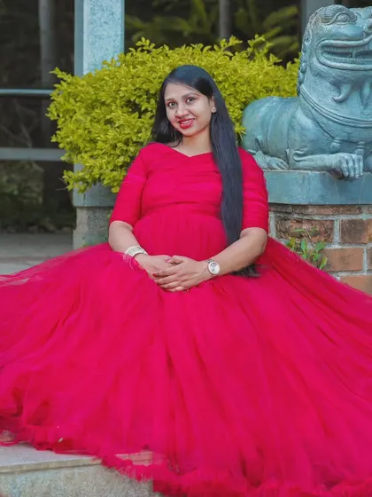 Seated on stone steps, the red flowy gown spreads out to create a beautiful pool of color. This demonstrates the versatility of the dress for various poses during your maternity session.