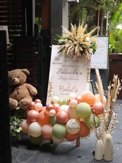 A beautiful welcome sign for Bhavika's baby shower, decorated with pampas grass and an earthy-toned balloon garland.