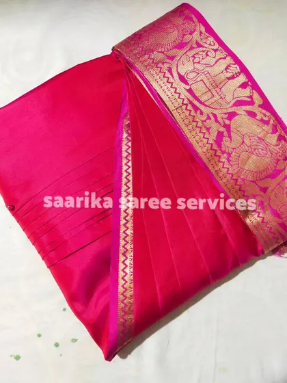 A stunning hot pink saree with a wide gold border. The pleats are perfectly set to make a bold statement.