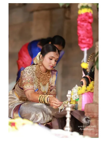 A candid moment of Vishnu Priya during her wedding puja at the Bhoganandeeshwara Temple. Her makeup is traditional and flawless, designed to hold up beautifully through all the ceremonies.
