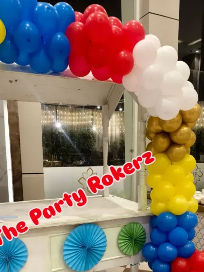A food cart decorated with a colorful balloon garland, perfect for a carnival or circus-themed party.