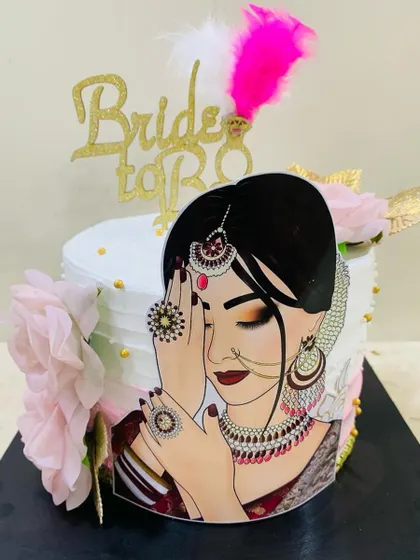 A chic and modern cake for a bride-to-be. This design features a stylish bridal illustration, delicate pink flowers, and elegant feather toppers for a memorable bridal shower.