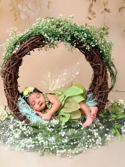 Our little Tinkerbell is dreaming sweet dreams. This setup features a newborn in a green fairy costume, complete with sparkling wings, sleeping in an enchanted wreath.