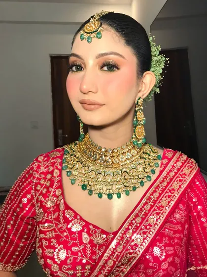 A frontal view of this elegant bridal makeup. The focus is on flawless skin and beautifully defined eyes, paired with heavy kundan jewelry.