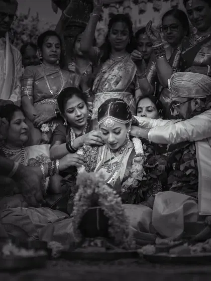 A black and white photo capturing the entirety of a ritual, with the couple surrounded by their family. This documentary-style shot tells the story of a community coming together.