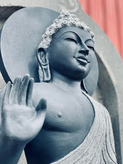 A close-up of a stone Buddha statue in the Abhaya mudra pose, which represents protection and fearlessness.