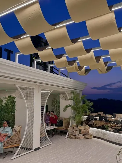 The undulating fabric ceiling provides shade and adds a soft, kinetic element to the design, contrasting with the solid forms of the architecture.