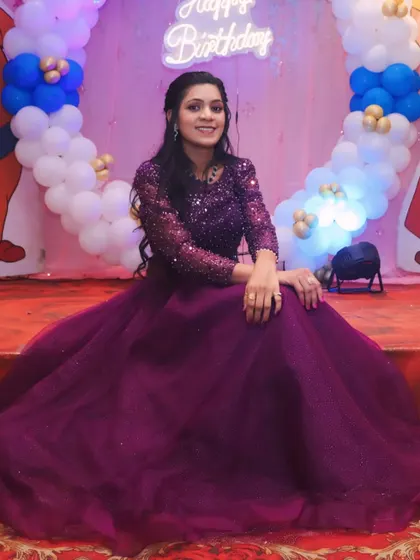 A seated portrait of the birthday girl in her gorgeous purple gown. The balloon backdrop adds to the festive and celebratory atmosphere.