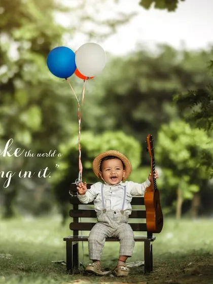 You make the world a little better by being in it. A joyful boy with a straw hat, ukulele, and balloons on a park bench.