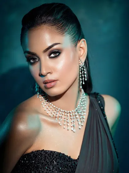 A close-up portrait against a cool-toned background, where the lighting creates a beautiful sheen on the skin and highlights the diamond jewelry.