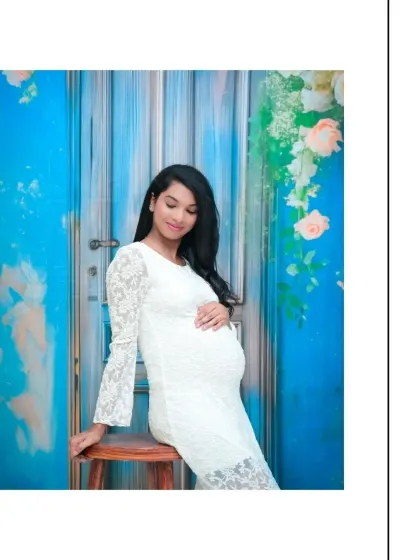 A relaxed and graceful seated portrait. The white lace dress and the bright blue backdrop create a striking contrast, resulting in a clean and contemporary maternity photo.