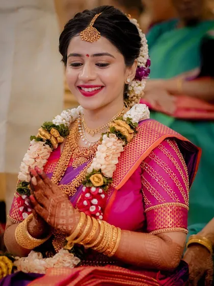 The bride, with hands joined in prayer, her face glowing with happiness and anticipation.