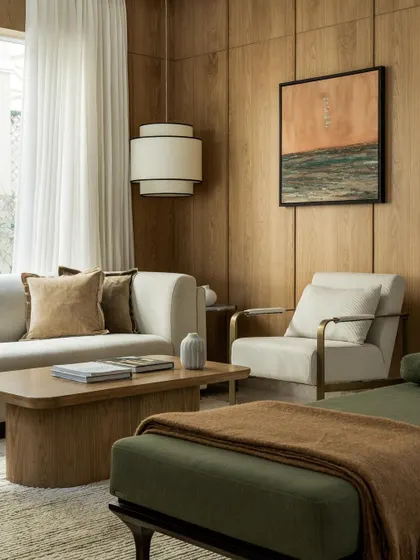 This wood-paneled living room from 2023 is a perfect example of creating a cozy, sophisticated space with a neutral palette and rich textures.
