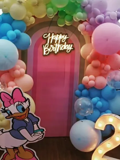 A cute and colorful setup featuring Daisy Duck. I used a rainbow pastel balloon arch against a pink backdrop with a 'Happy Birthday' neon sign and a large light up number '2'.
