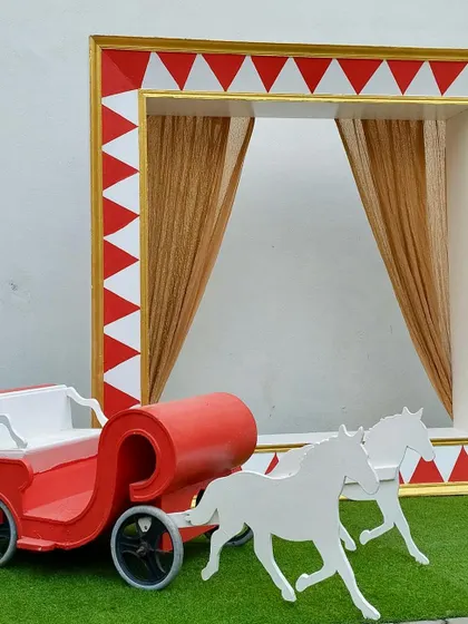 This red and white carriage, paired with a circus-themed frame backdrop, creates a fun and festive photo opportunity for a carnival or circus party.