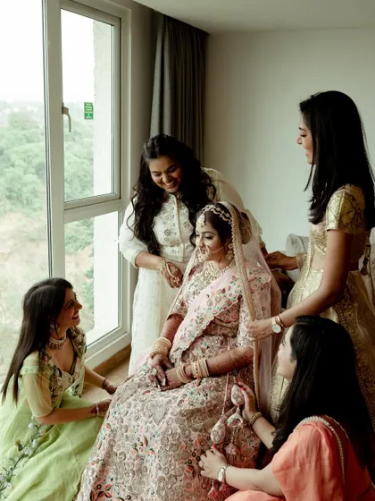 A heartwarming moment of the bride surrounded by her bridesmaids, sharing laughter and joy before the ceremony.