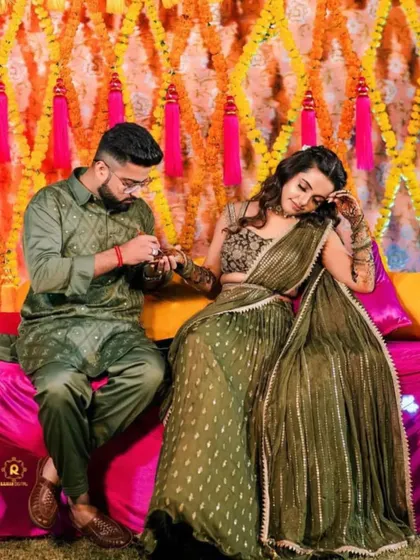 A candid moment from a mehandi ceremony where the groom is applying a small bit of henna on the bride's hand, a lovely tradition.