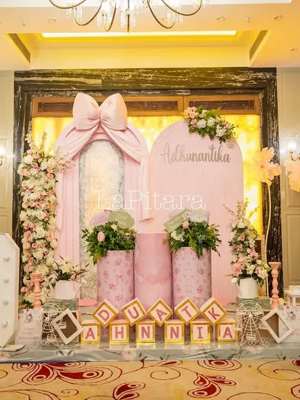 The full stage setup for the 'Bow'teaful' party, combining large marquee numbers, personalized signs, and beautiful floral decor.