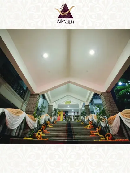 The grand staircase entrance of a venue, decorated with flowing white and yellow drapes and marigold garlands, creating a traditional and stately welcome.