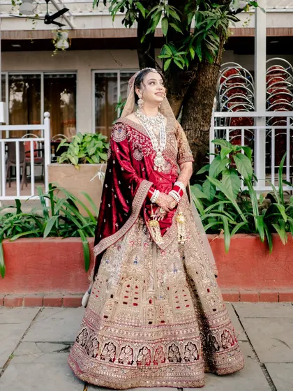 A full-length portrait of the bride looking regal in her heavily embroidered wedding lehenga.