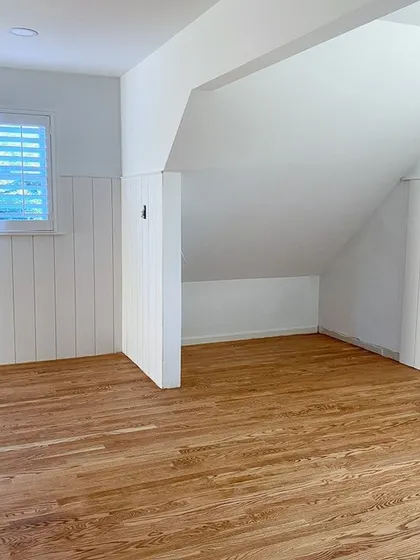 This image shows a natural oak wood flooring in an empty room, highlighting the clean installation and the beautiful grain of the wood. This type of flooring is a versatile base for any interior style, from modern to traditional.