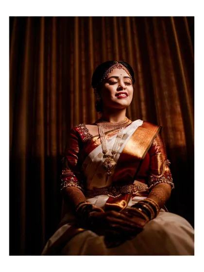 A dramatic bridal portrait with beautiful side lighting, highlighting the bride's serene expression and the rich texture of her saree.