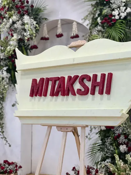 The "Mitakshi" name board, a key element in a naming ceremony designed around the meaning of the baby's name. The red lettering and surrounding florals created a powerful and beautiful statement.