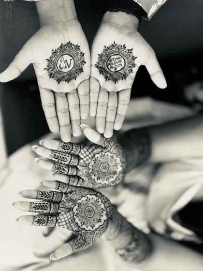 A beautiful black and white shot of a couple's mehndi. The groom has the bride's initial, and the bride has a detailed mandala design, symbolizing their union.