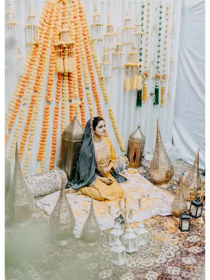 A beautiful portrait of a Kashmiri bride during her Mehendi ceremony. The traditional decor with marigolds and brass lanterns creates a stunning setting.