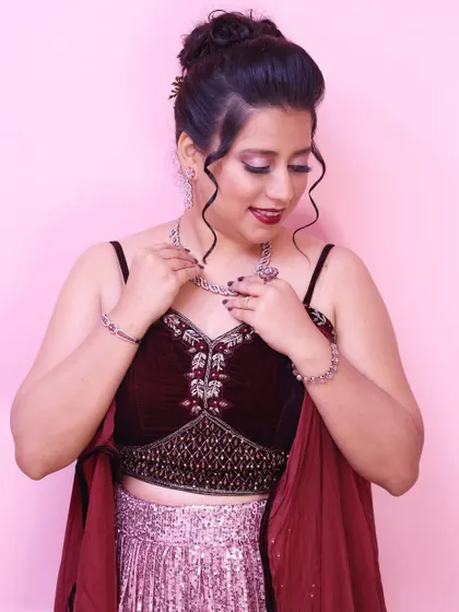Adjusting her necklace, this shot gives a great view of the elegant updo and the shimmering details of her outfit.