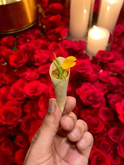 Our patented Wild Mushroom & Truffle Galouti Cornet, a sophisticated and flavorful canapé served against a backdrop of red roses at an intimate dinner party.