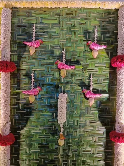 We love adding unique details to our decor. This close-up shows small, bird-shaped floral hangings made from pink flowers, adding a charming and artistic touch to a traditional pooja backdrop.