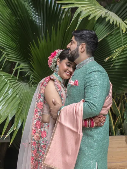 A warm and affectionate embrace between the couple, set against a backdrop of tropical foliage. This intimate portrait highlights their close bond and happiness.