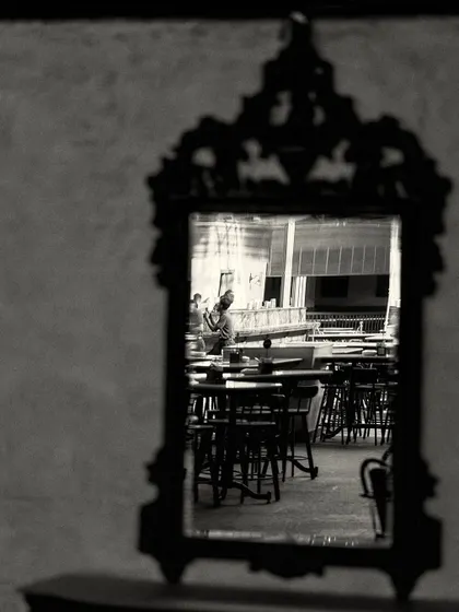 A reflection of the bar's seating area in a dark, intricately framed mirror, creating a picture within a picture.