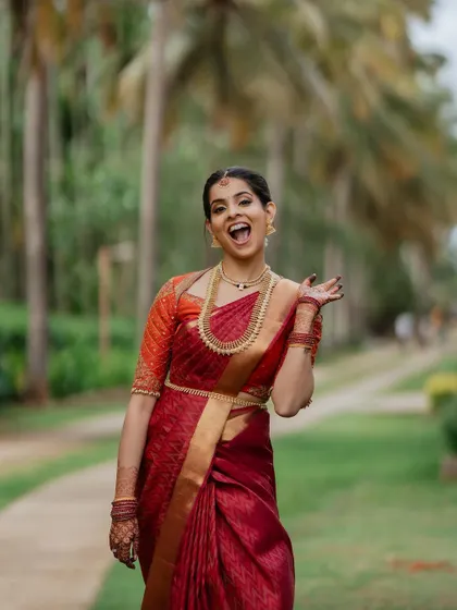A smile that lights up the day. This candid bridal portrait captures the bride's infectious happiness and natural beauty in her stunning red saree.