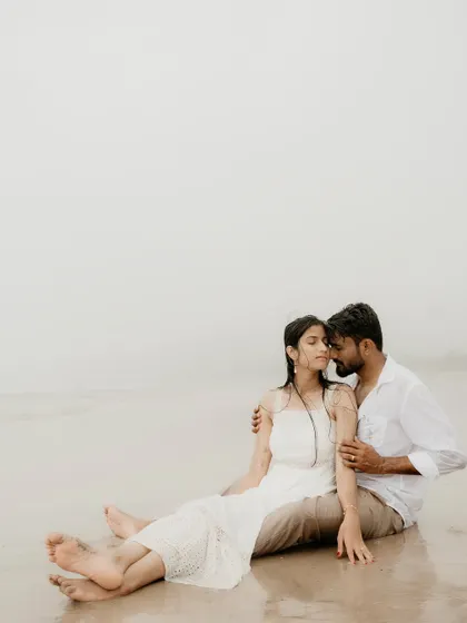 A tender embrace on the foggy beach. This intimate shot highlights their closeness and the romantic, moody atmosphere of the seaside.