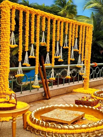 A traditional Haldi setup with a backdrop of marigold garlands and hanging jasmine strings. The golden urli and seating arrangement complete this classic and auspicious look.